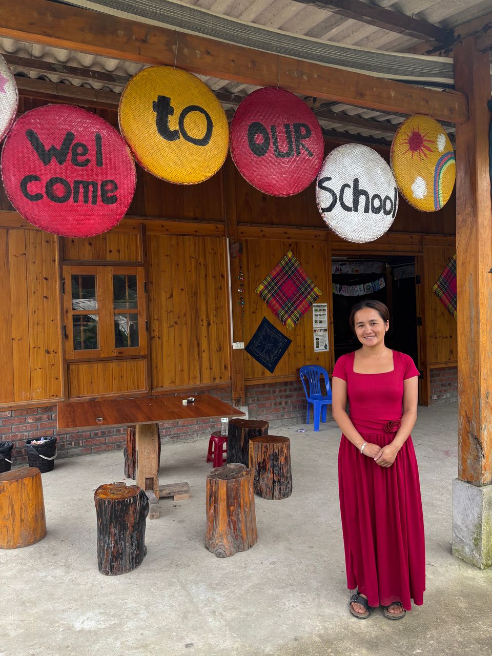 Des paniers tressés peints à la main indiquant « Bienvenue dans notre école » à l'entrée de l'école, Miss Ha juste en dessous.